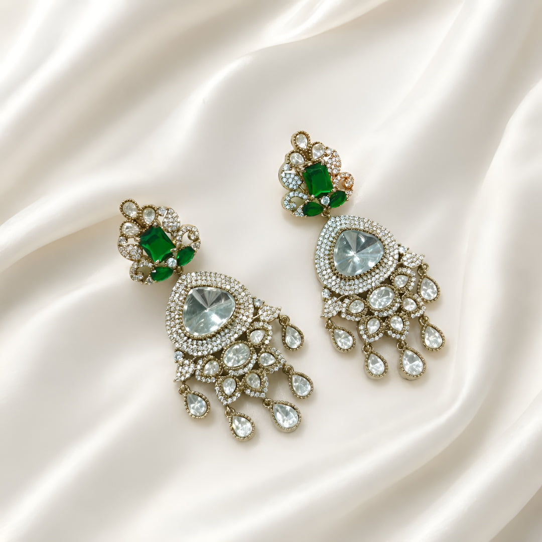 Luxury gold-plated statement earrings with emerald green stones, Kundan stones, sparkling American diamonds, and teardrop danglers for women.