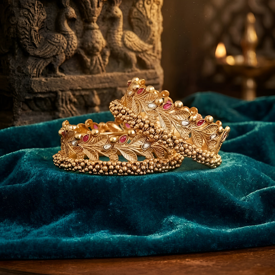 Gold-plated leaf design kada bangles with red and white stone embellishments for women.