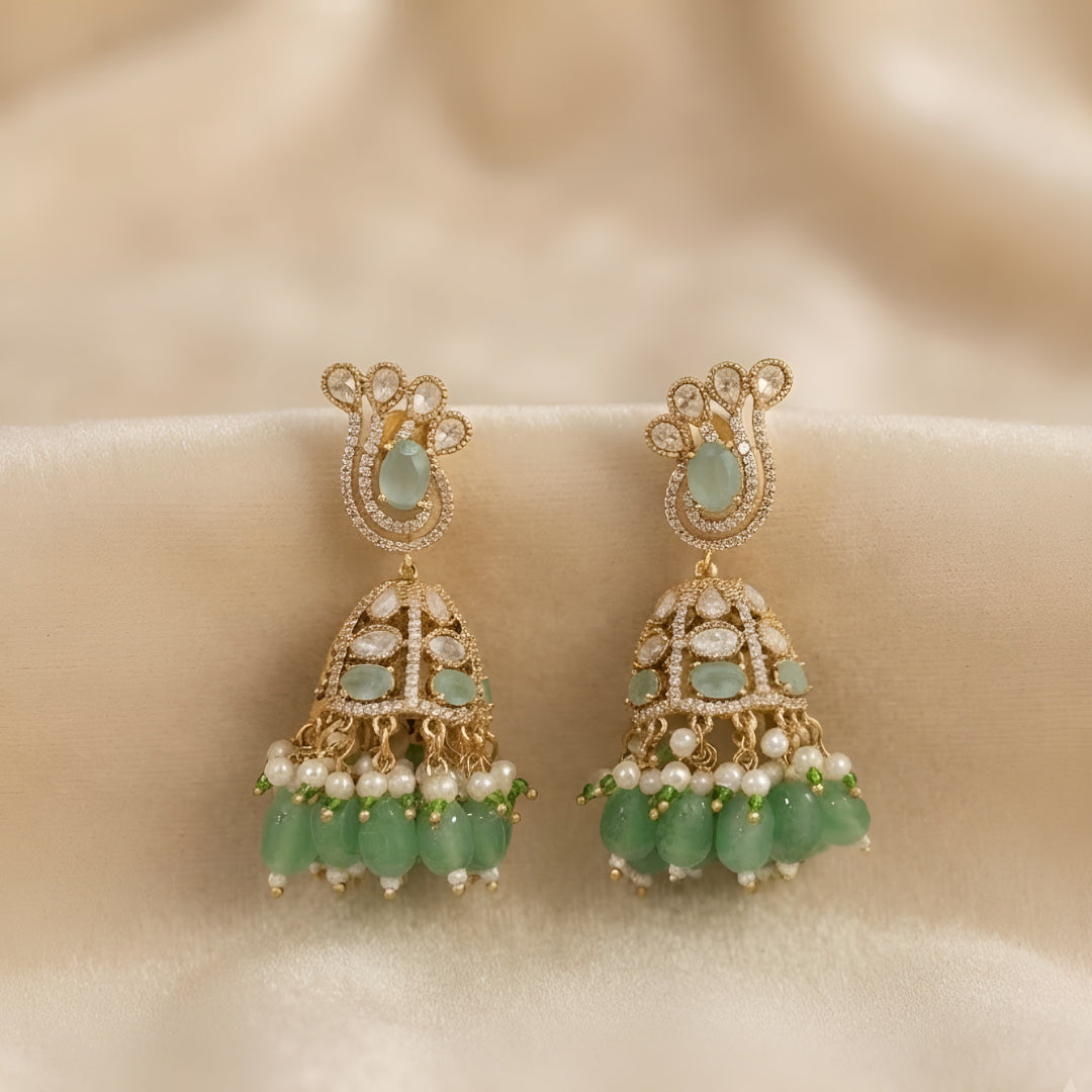 Antique gold Kundan jhumka earrings featuring aqua green stones, pearl accents, and green bead drops for women.