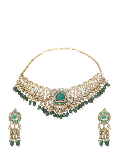 Detailed gold-toned statement necklace with intricate white stone embellishments and a prominent green teardrop centerpiece, finished with dangling green beads and pearls, paired with matching ornate drop earrings, displayed on a plain light background.