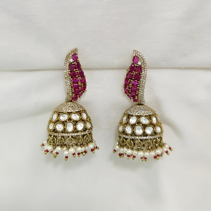 Antique gold Kundan jhumka earrings with ruby stones, sparkling American diamonds, and pearl drop fringe for women.