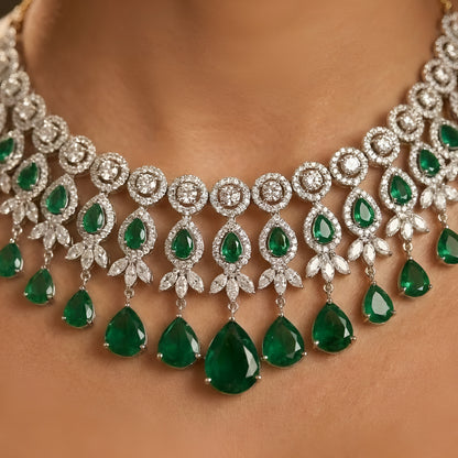 Silver-tone choker necklace and earrings set featuring sparkling clear crystals and emerald green teardrop stones in an elegant bridal jewelry design.