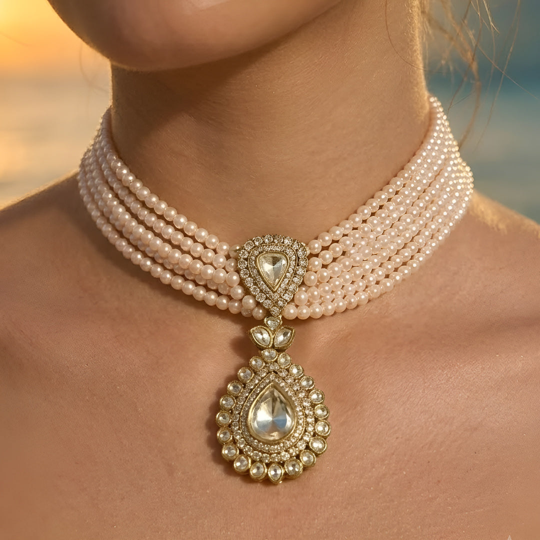 Multi-strand pearl choker necklace featuring a teardrop Kundan pendant with matching stud earrings on a white background.