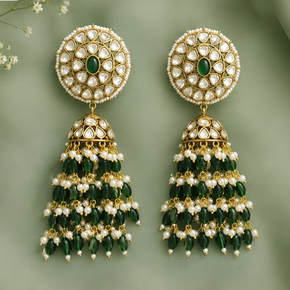 Green Kundan jhumka earrings with gold plating, emerald green center stone, pearl accents, and layered green bead tassels for bridal and festive wear.