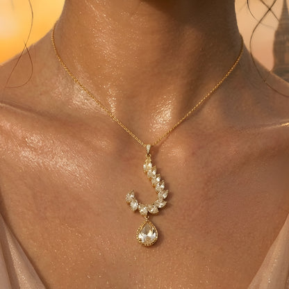 Gold-toned leaf design pendant necklace set with teardrop crystal pendant and matching drop earrings on a white background.