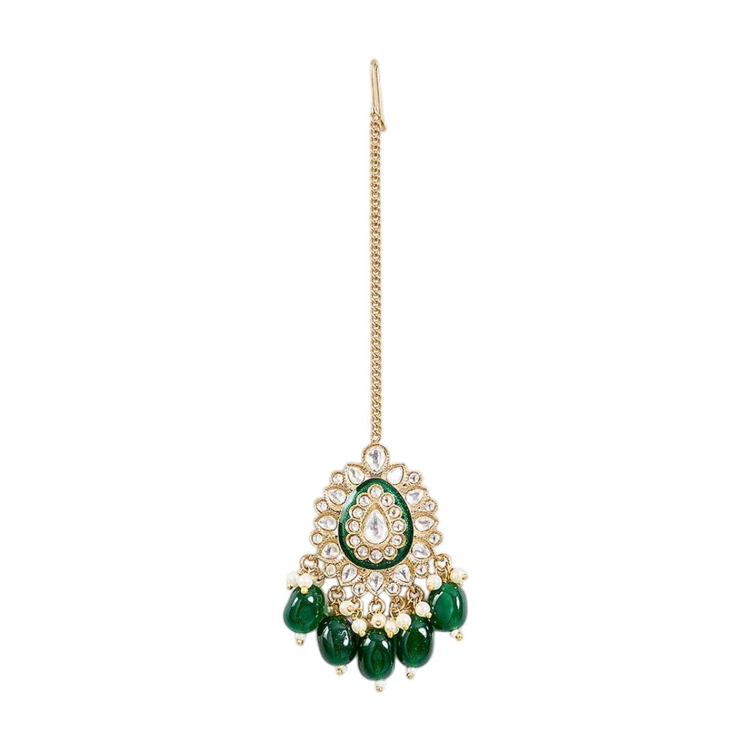 Gold-toned Kundan maang tikka with green enamel detailing, teardrop stones, pearl accents, and emerald-green bead drops for bridal and festive wear.