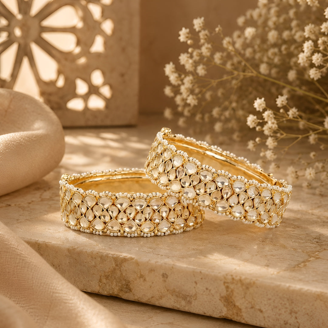 Gold-plated Kundan bangles with teardrop stones and pearl bead detailing for women, ideal for bridal and festive wear.