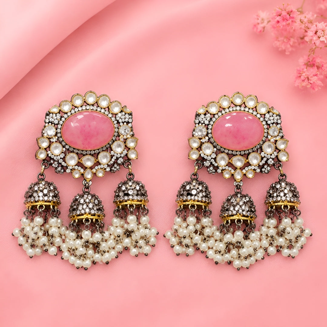 Pink Kundan jhumka earrings with antique gold finish, oval pink stone, sparkling Kundan crystals, and pearl tassel drops for bridal and festive wear.