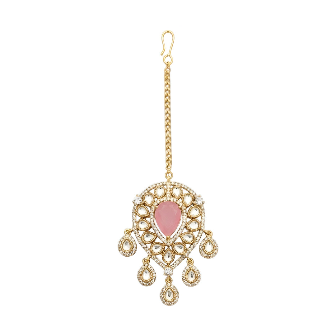 Gold-plated bridal maang tikka with pink pear-shaped stone, Kundan-style teardrop crystals, and elegant dangling accents for weddings and festive wear.