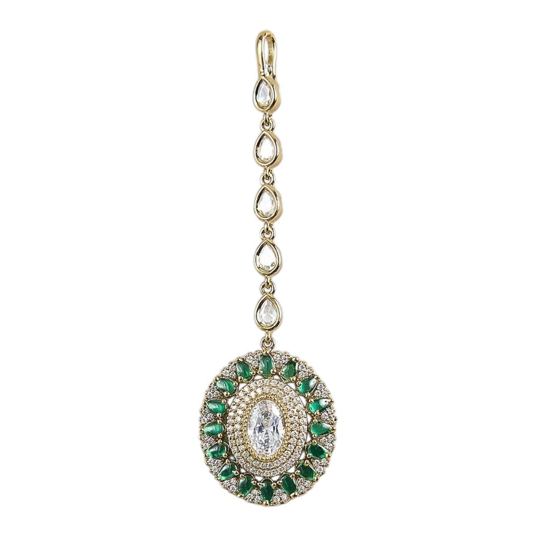 Gold-plated green American diamond bridal maang tikka with oval crystal centerpiece and green marquise stones on a white background.