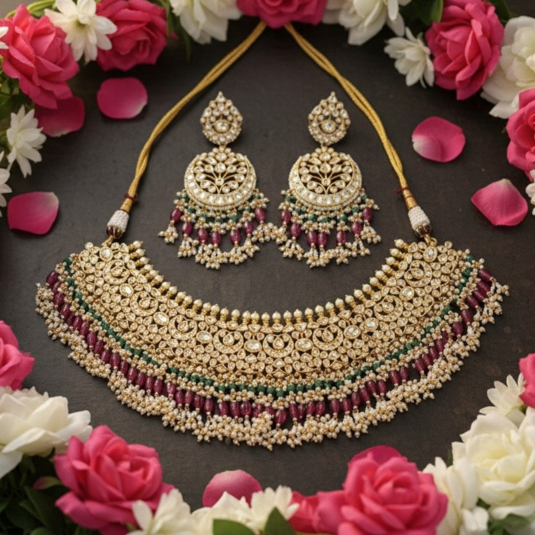 "Traditional gold-tone kundan bridal necklace set with ruby red and emerald green beads, paired with matching chandbali earrings on maroon silk background"