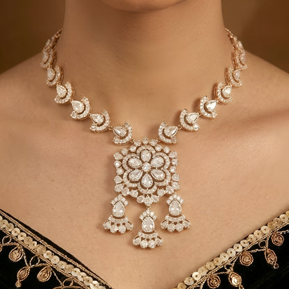Gold-tone Kundan floral necklace set featuring a statement pendant with dangling accents and matching drop earrings on a white background.