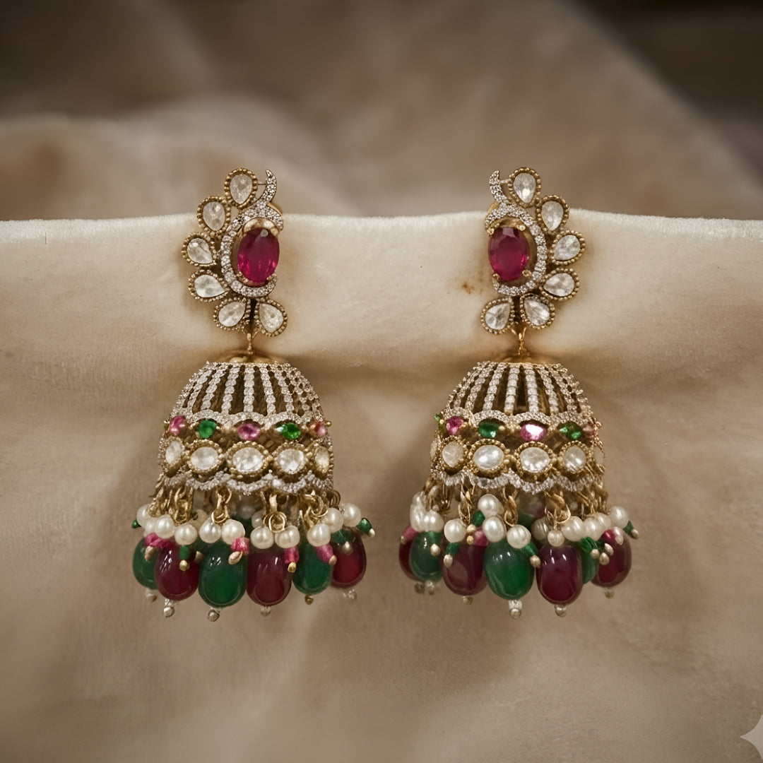 Antique gold Kundan jhumka earrings with ruby center stones, green bead drops, pearl accents, and traditional bridal design for women.