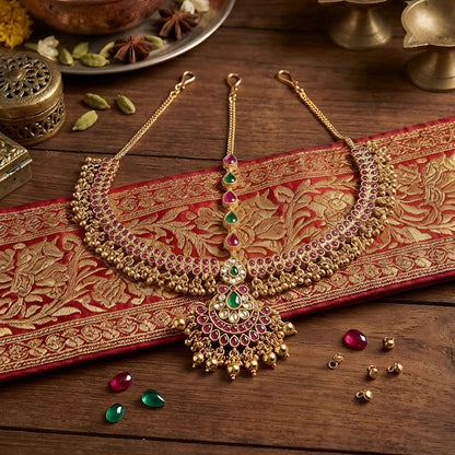 Traditional gold-plated Matha Patti with pink and green Kemp stones and matching maang tikka, perfect for bridal and festive wear.