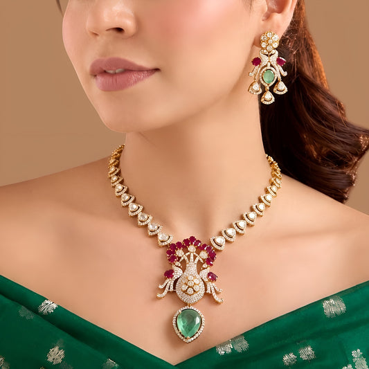 Gold-finish peacock pendant necklace set with ruby-pink stones, carved green drop and matching earrings by Auraa Trends