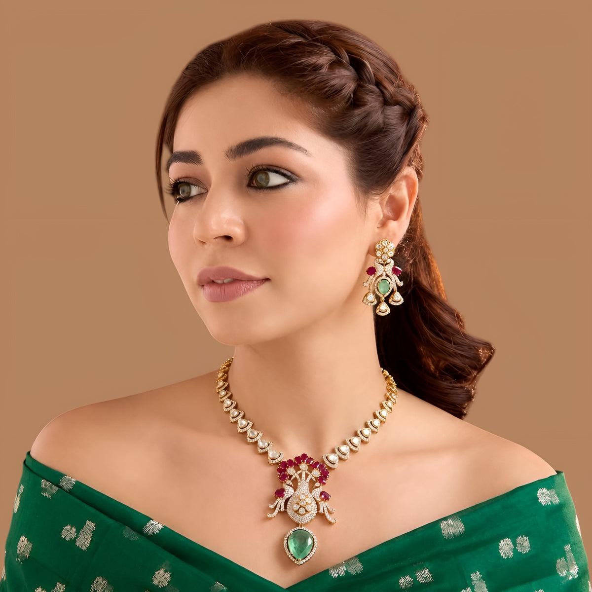 Gold-finish peacock pendant necklace set with ruby-pink stones, carved green drop and matching earrings by Auraa Trends
