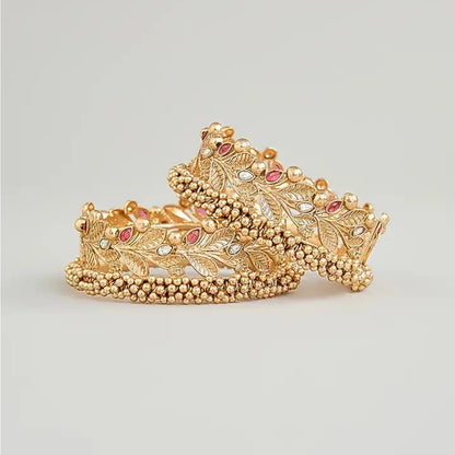 Gold-plated leaf design kada bangles with red and white stone embellishments for women.
