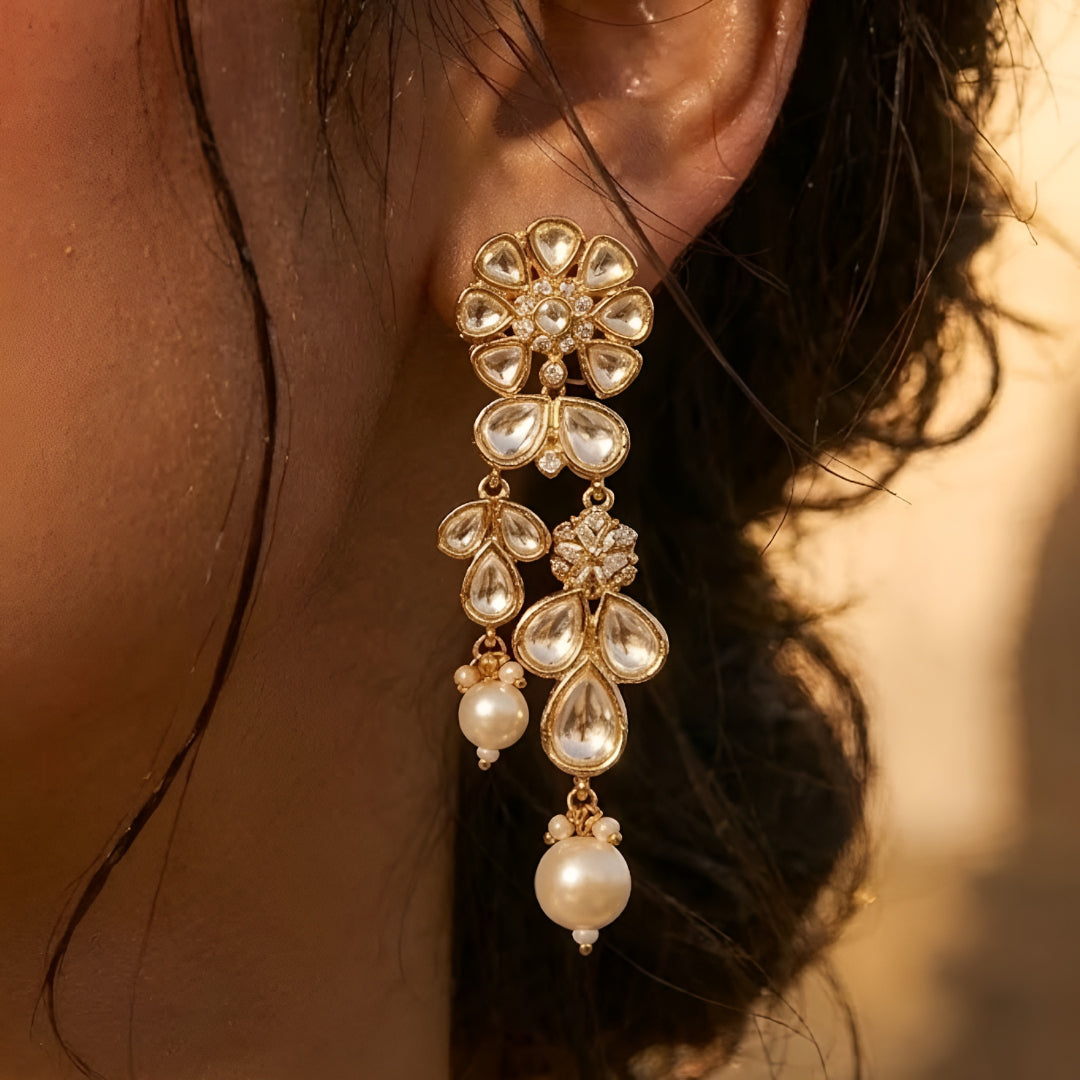 Gold-toned Kundan pearl choker necklace set featuring floral motifs, teardrop stones, pearl danglers, and matching earrings on a white background.