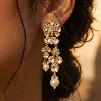 Gold-toned Kundan pearl choker necklace set featuring floral motifs, teardrop stones, pearl danglers, and matching earrings on a white background.