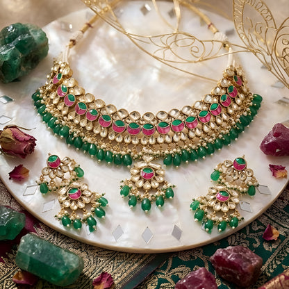 Traditional Kundan choker necklace set with pink stone detailing, green bead drops, and matching earrings in gold-plated finish for bridal wear.
