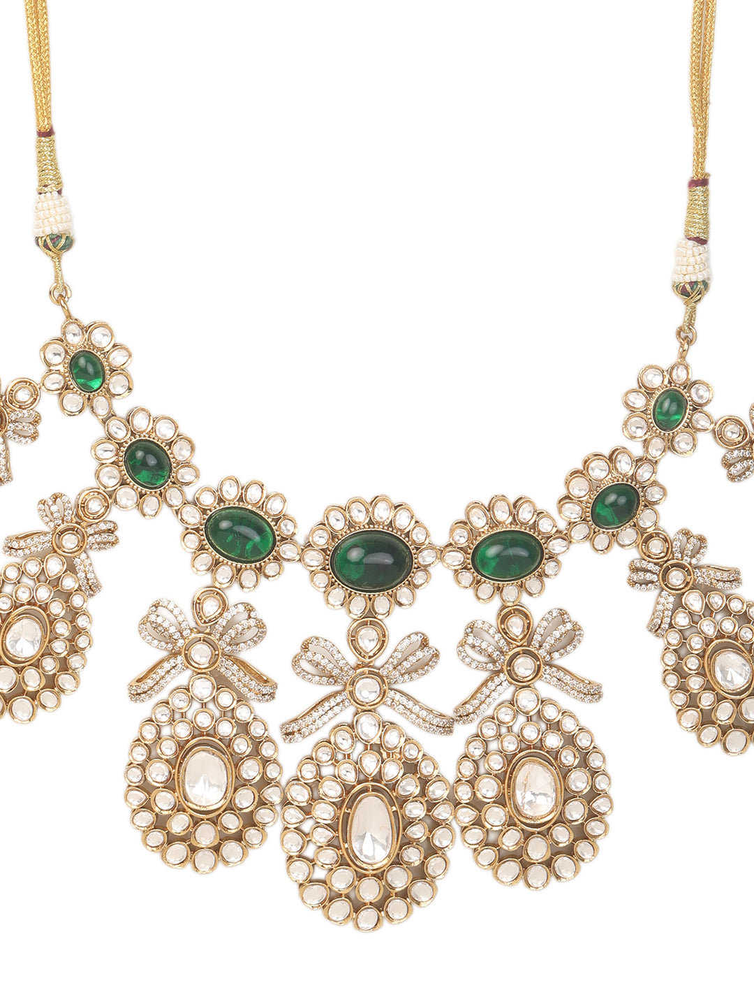 Gold-toned necklace with a braided cord and adjustable tassel tie, featuring intricate white stone detailing with oval green gemstones and multiple dangling teardrop motifs, paired with matching drop earrings, displayed on a plain light background.
