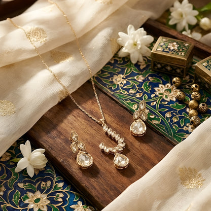Gold-toned leaf design pendant necklace set with teardrop crystal pendant and matching drop earrings on a white background.