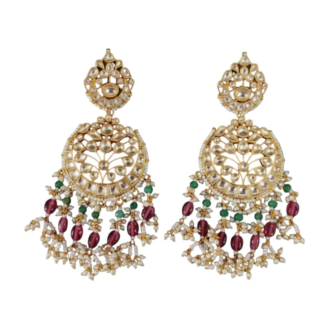 "Traditional gold-tone kundan bridal necklace set with ruby red and emerald green beads, paired with matching chandbali earrings on maroon silk background"