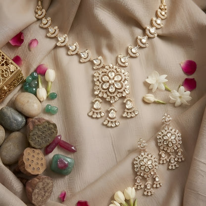 Gold-tone Kundan floral necklace set featuring a statement pendant with dangling accents and matching drop earrings on a white background.