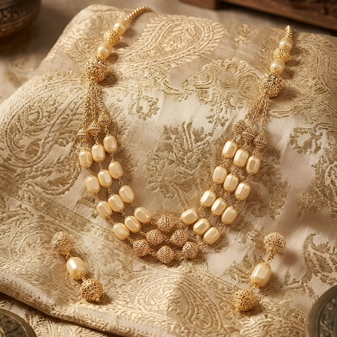 Elegant multi-layer ivory pearl beaded necklace set with gold-tone filigree accents and matching drop earrings for women.