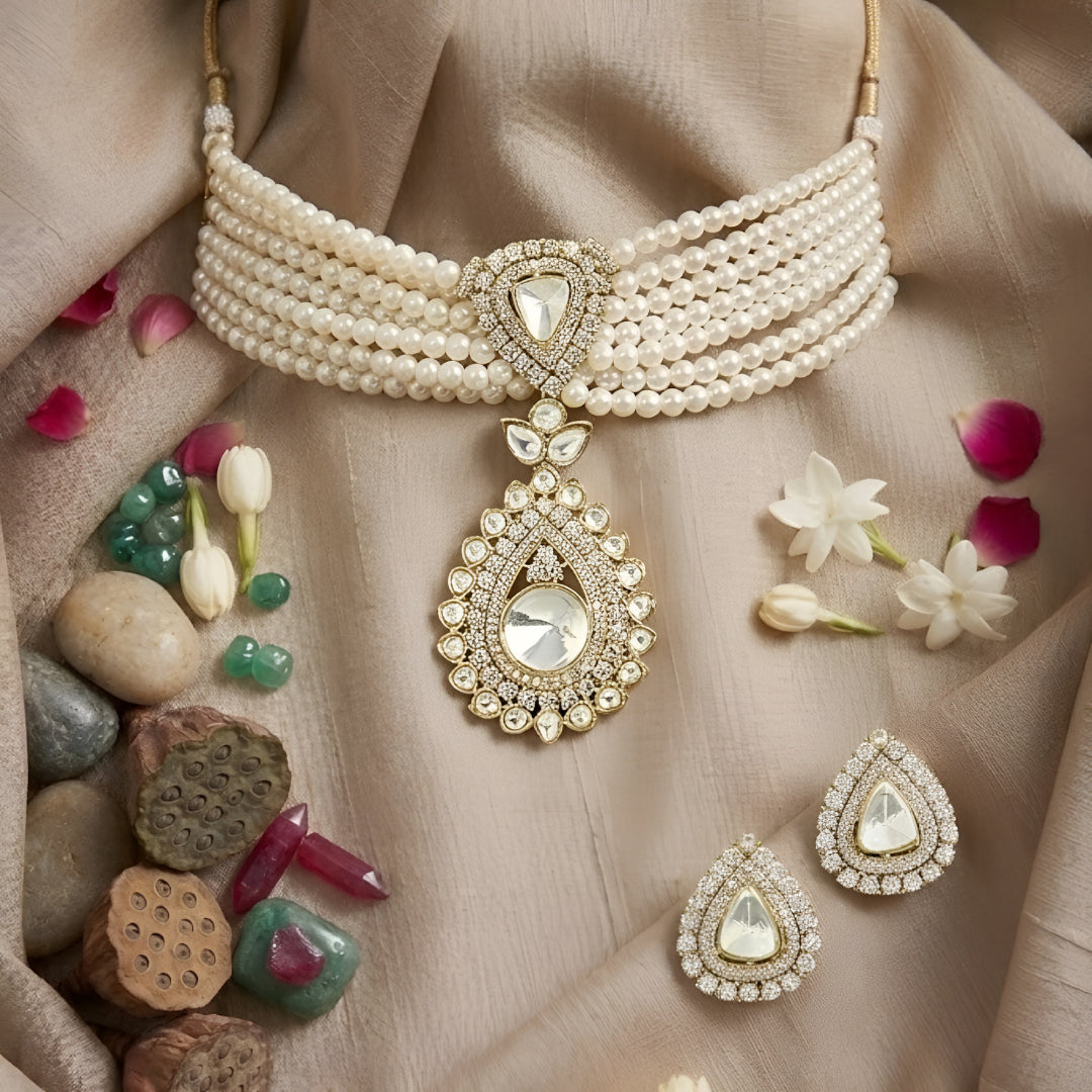 Multi-strand pearl choker necklace featuring a teardrop Kundan pendant with matching stud earrings on a white background.