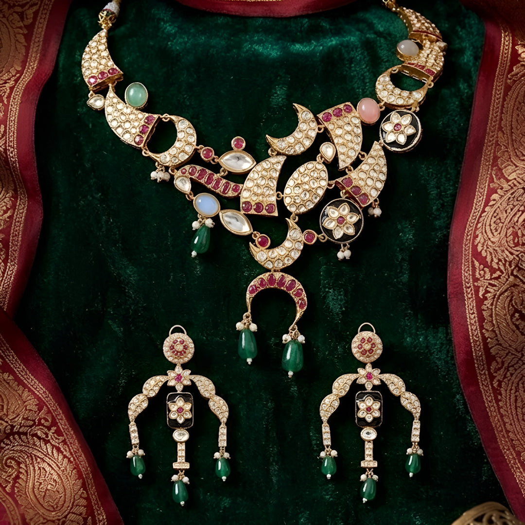 Designer gold-plated kundan necklace set with floral enamel motifs, pink stone accents, sparkling white kundan work, green bead drops, and matching statement earrings.