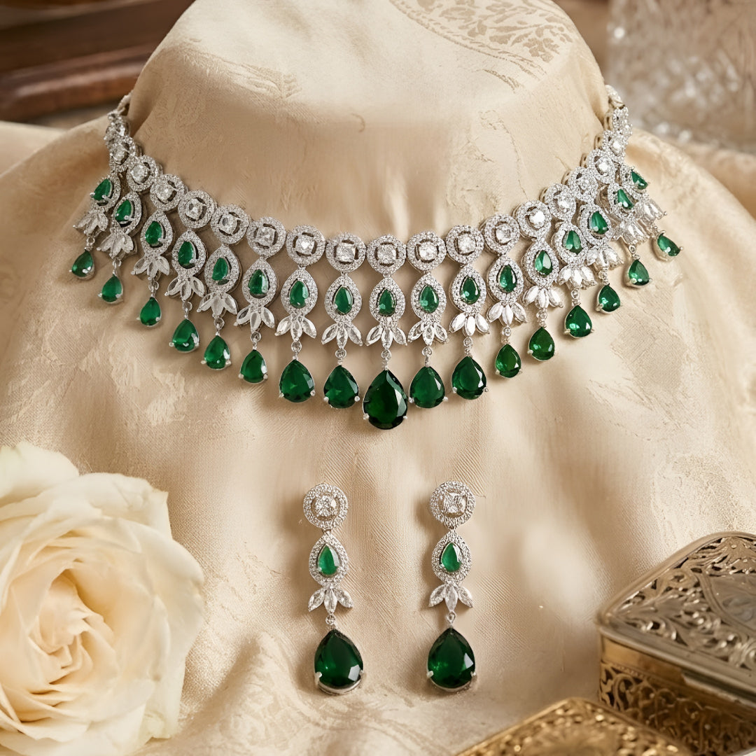 Silver-tone choker necklace and earrings set featuring sparkling clear crystals and emerald green teardrop stones in an elegant bridal jewelry design.