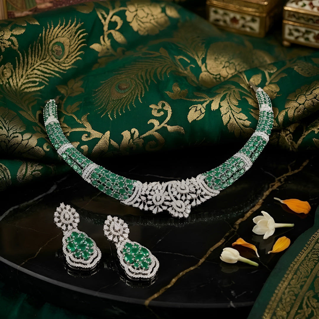 Silver-toned emerald green crystal choker necklace set featuring sparkling stone detailing and matching statement drop earrings on a white background.