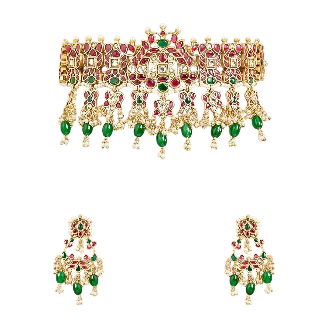Traditional gold-plated Kundan choker necklace set with red and green stones, dangling green beads, and matching chandbali earrings for bridal wear.