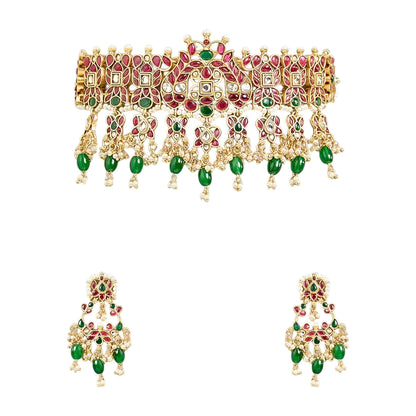 Traditional gold-plated Kundan choker necklace set with red and green stones, dangling green beads, and matching chandbali earrings for bridal wear.