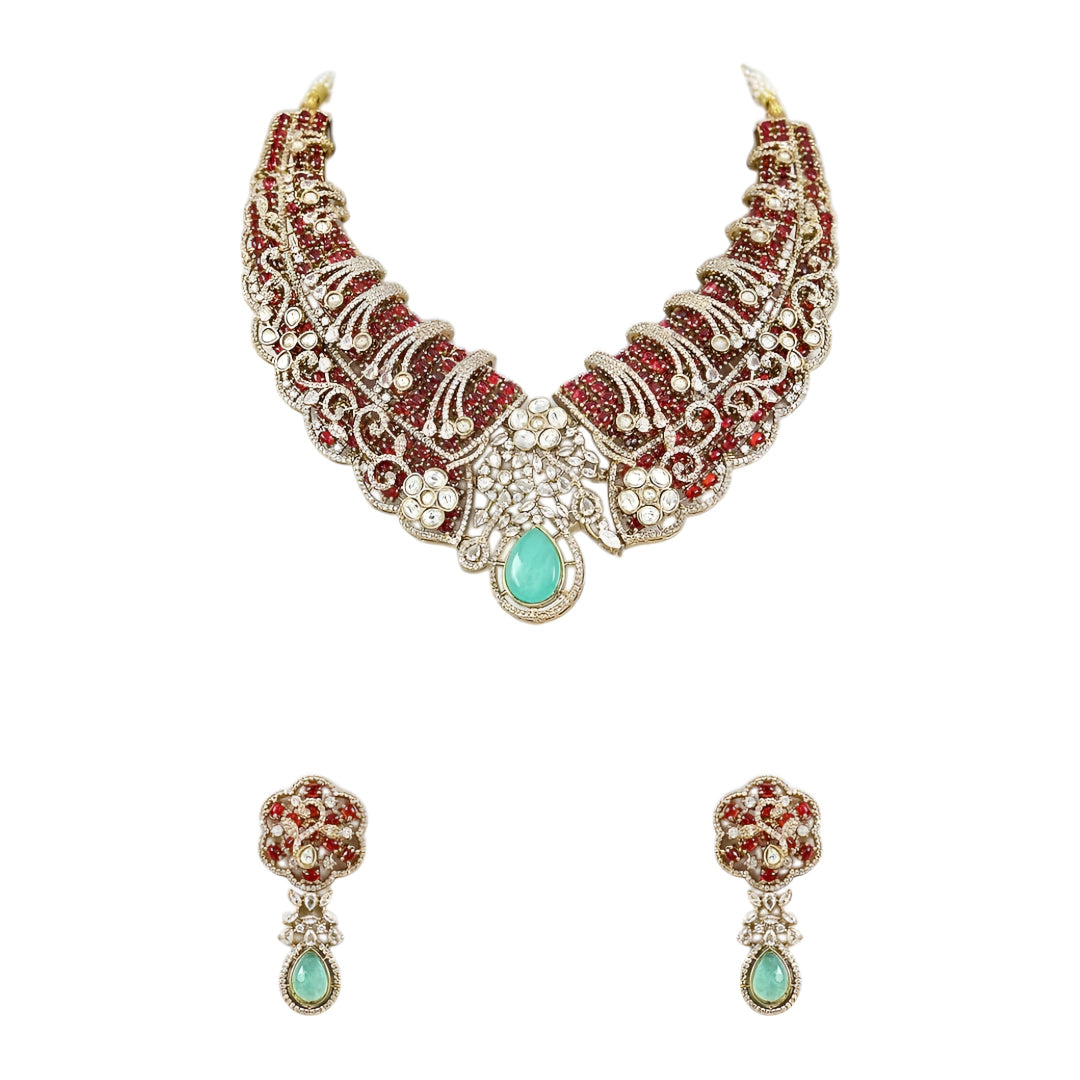 Designer ruby red kundan choker necklace set with sparkling crystal detailing, mint green teardrop gemstone centerpiece, and matching earrings for bridal and festive occasions.