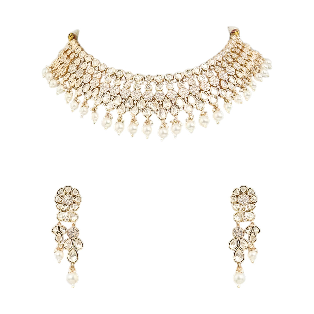Gold-toned Kundan pearl choker necklace set featuring floral motifs, teardrop stones, pearl danglers, and matching earrings on a white background.