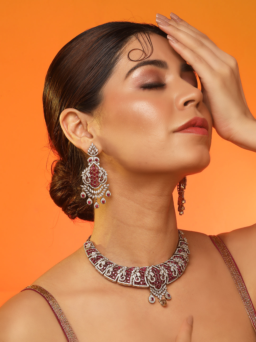 Gold-tone statement necklace set with pink ruby-style stones and clear crystals in an intricate floral design, paired with matching chandelier earrings featuring drop accents.