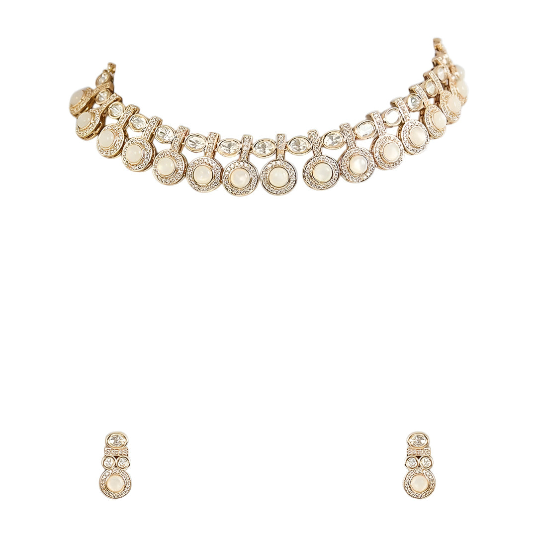 Gold-tone statement necklace set with ivory cabochon stones, crystal embellishments, and matching earrings on white background.