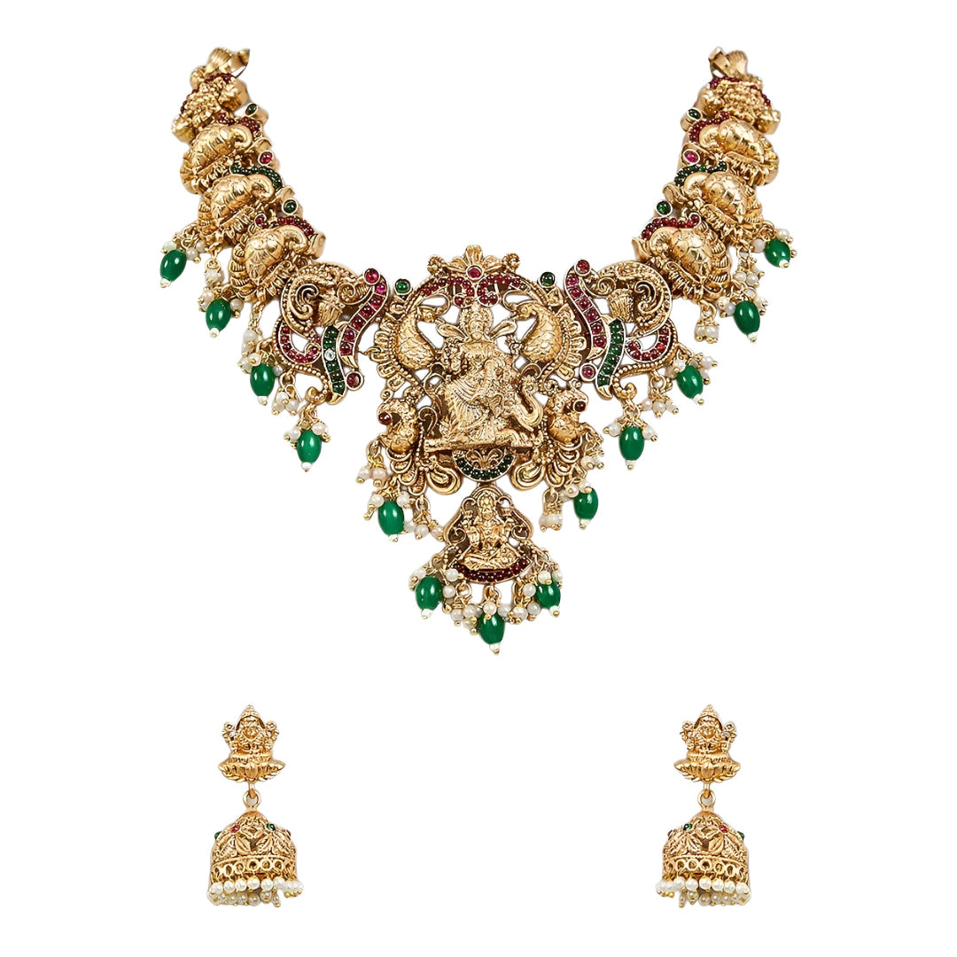 Traditional South Indian Temple Jewellery Lakshmi Necklace Set with matching Jhumka Earrings, antique gold finish, green bead drops, and ruby stone embellishments for bridal and festive wear.
