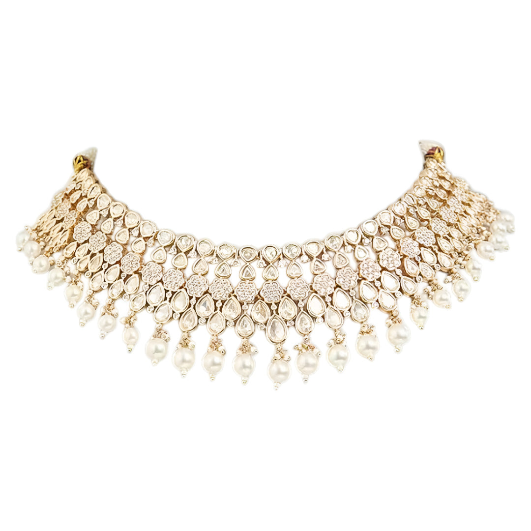Gold-toned Kundan pearl choker necklace set featuring floral motifs, teardrop stones, pearl danglers, and matching earrings on a white background.