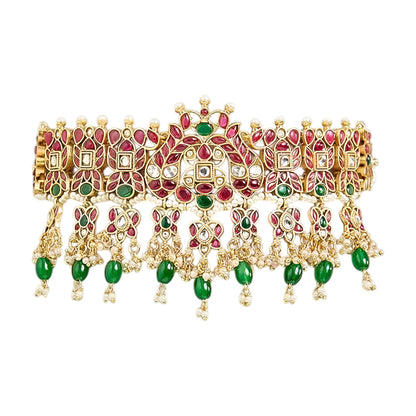 Traditional gold-plated Kundan choker necklace set with red and green stones, dangling green beads, and matching chandbali earrings for bridal wear.