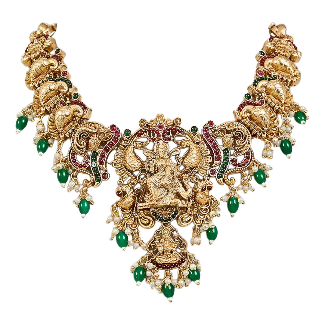 Traditional South Indian Temple Jewellery Lakshmi Necklace Set with matching Jhumka Earrings, antique gold finish, green bead drops, and ruby stone embellishments for bridal and festive wear.