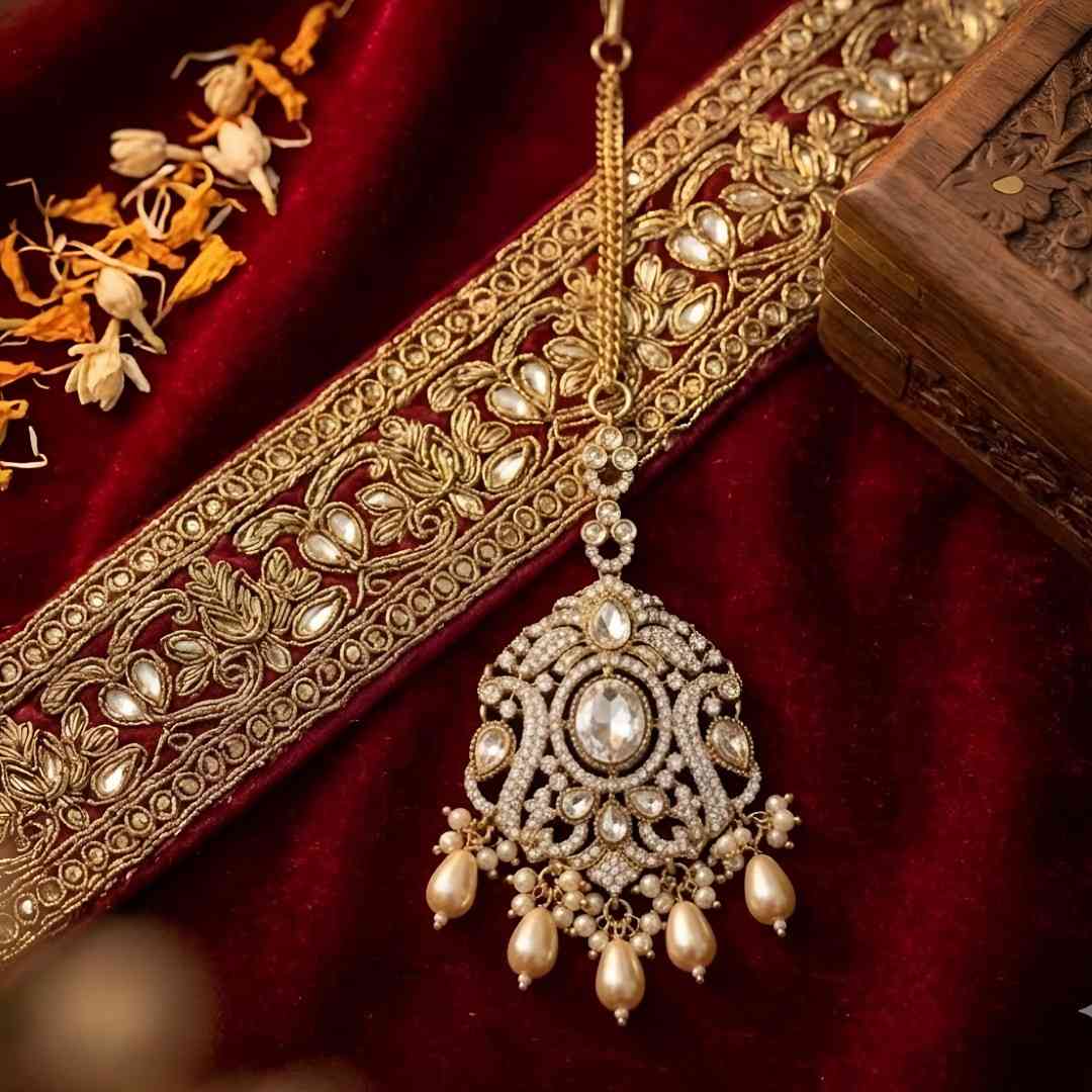 Gold plated Kundan Maang Tikka with white stone, crystal detailing and pearl drops for bridal wedding and traditional ethnic wear.