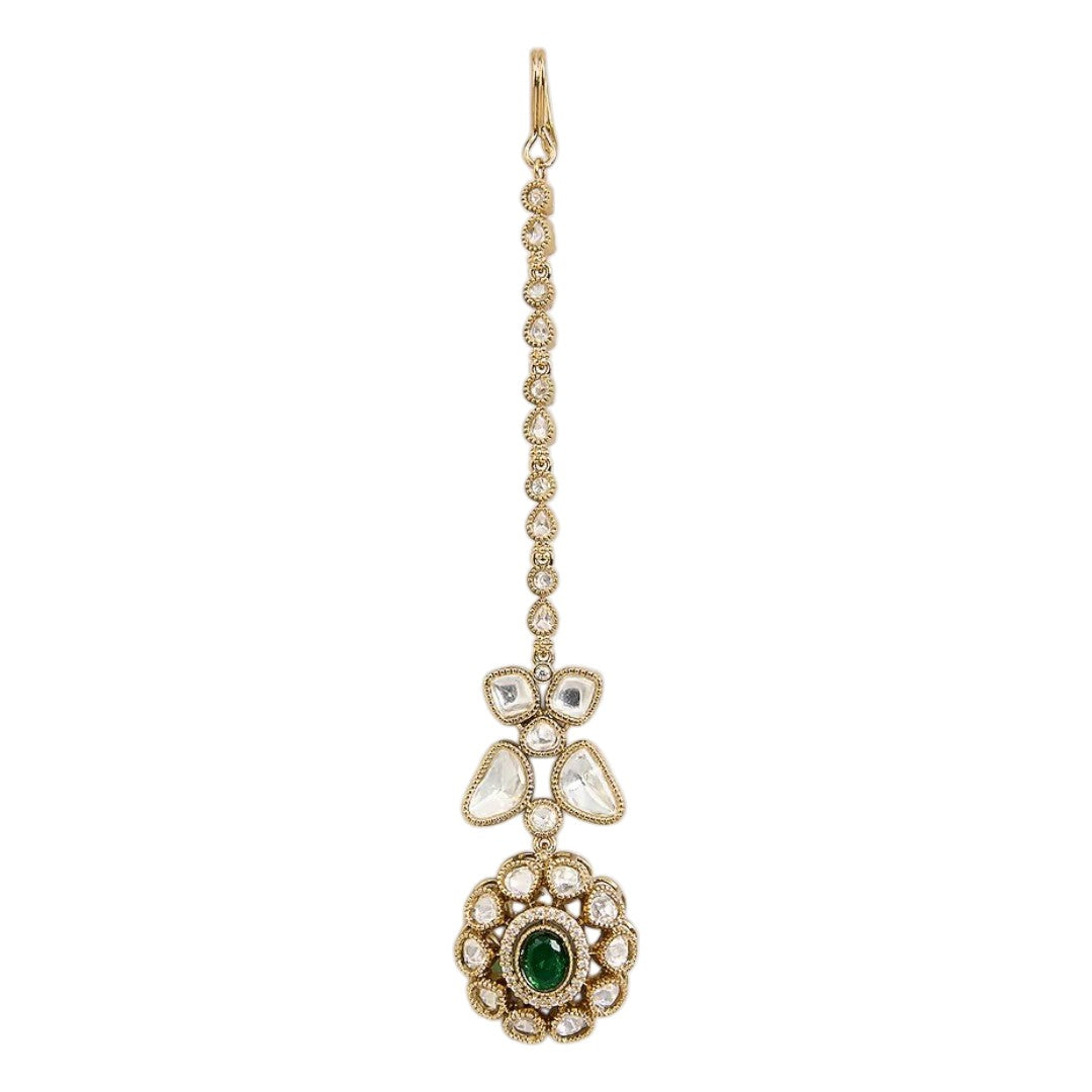 "Gold-toned maang tikka with polki clover motif and floral emerald-centered pendant, traditional Indian bridal jewelry"