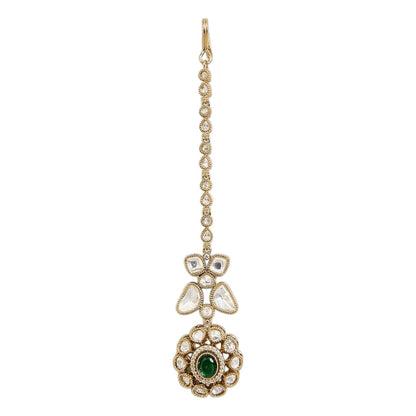 "Gold-toned maang tikka with polki clover motif and floral emerald-centered pendant, traditional Indian bridal jewelry"
