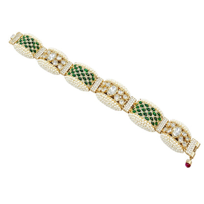 "Gold-tone bridal bracelet with pearl, emerald green, and white kundan stone panels and ruby drop clasp"