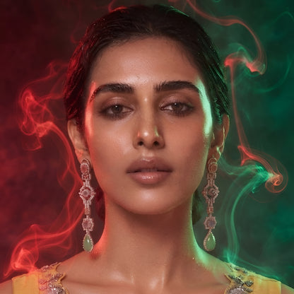 "Long gold-tone jhumka chandelier earrings with pink stones, CZ detailing, and green teardrop stone drop, front-facing pair