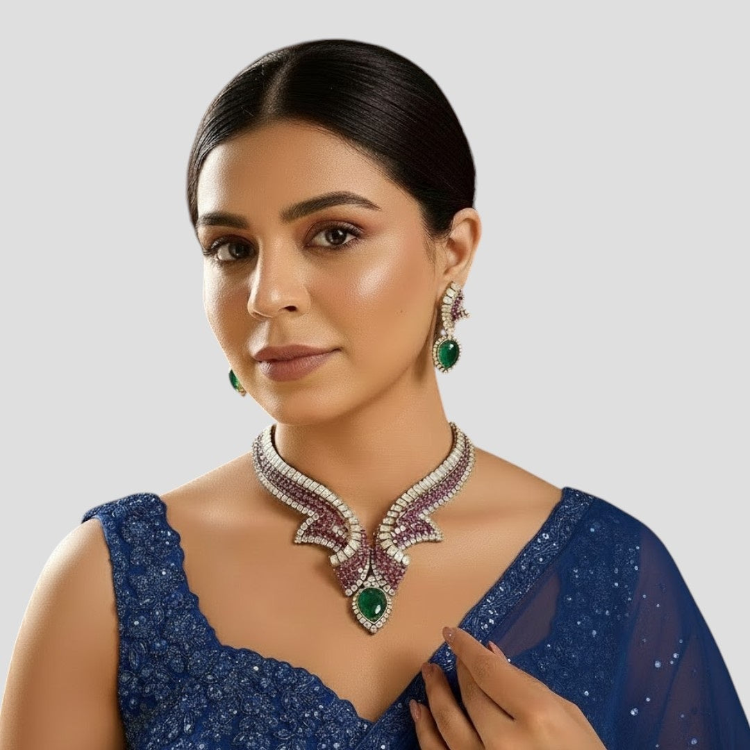 "Gold-plated designer necklace set with ruby stones, white crystals, and emerald teardrop centerpiece, paired with matching earrings"