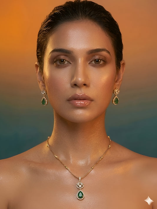 Gold-plated necklace set featuring emerald green teardrop pendant and matching drop earrings embellished with American diamonds.